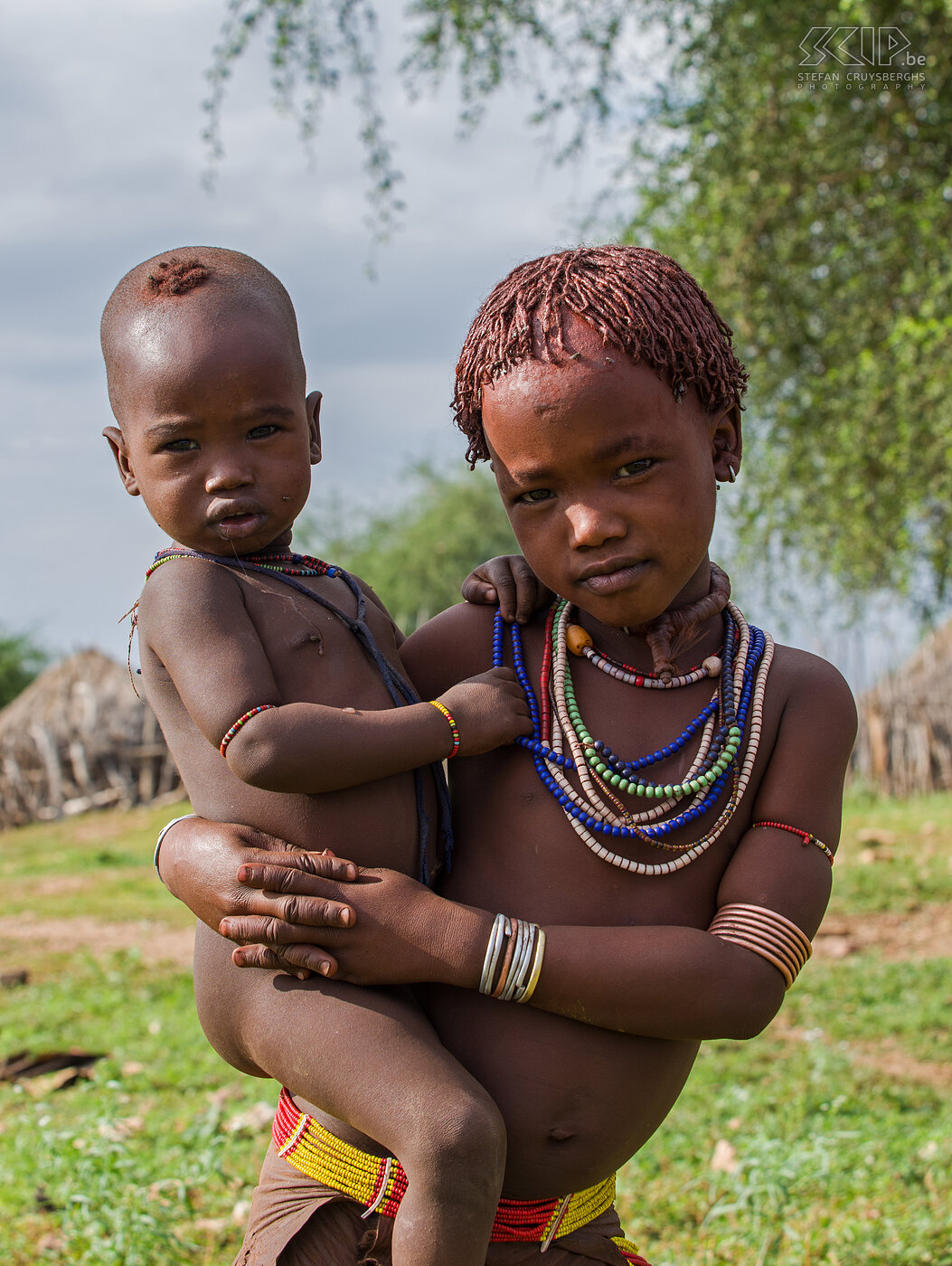 Turmi - Hamer girl with baby Near the town of Turmi we visited a village of the Hamer tribe. The Hamer (approx. 35,000) live in the center of the Omo Valley in Ethiopia. The women look beautiful with metal straps to upper arms and ankles, various colorful necklaces, leather skirts decorated with shells and beads and hairstyles made with red clay. Stefan Cruysberghs